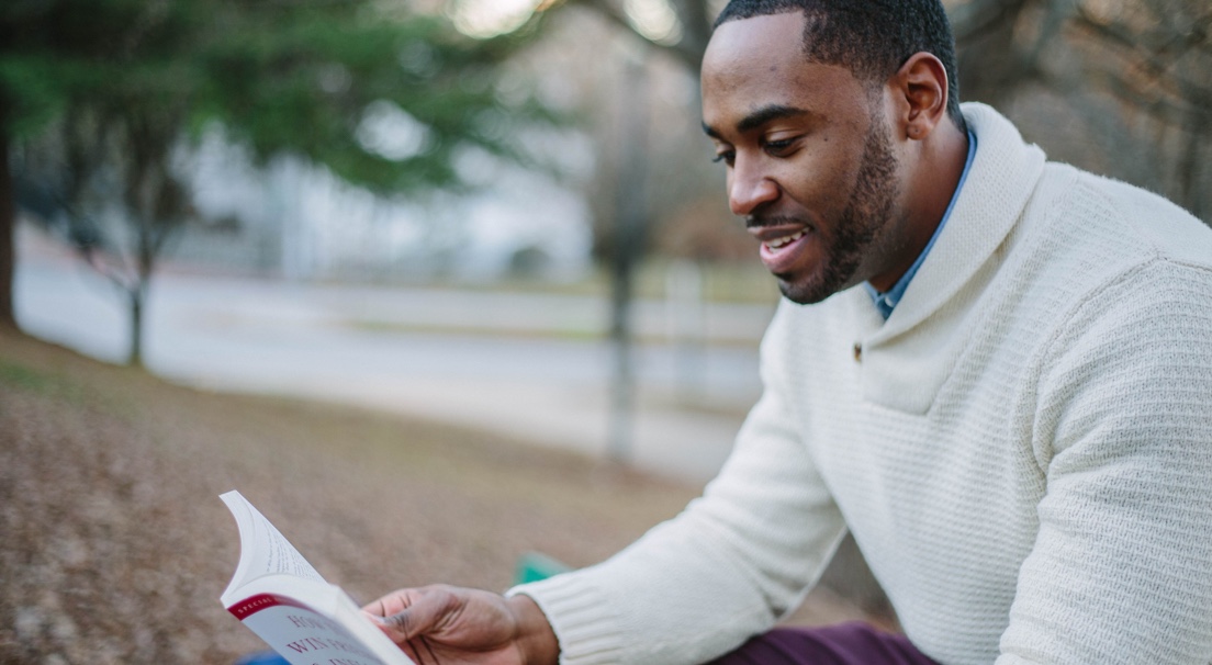 A black male student reading a book.