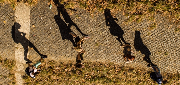 A group of people walking with shadow on the ground.